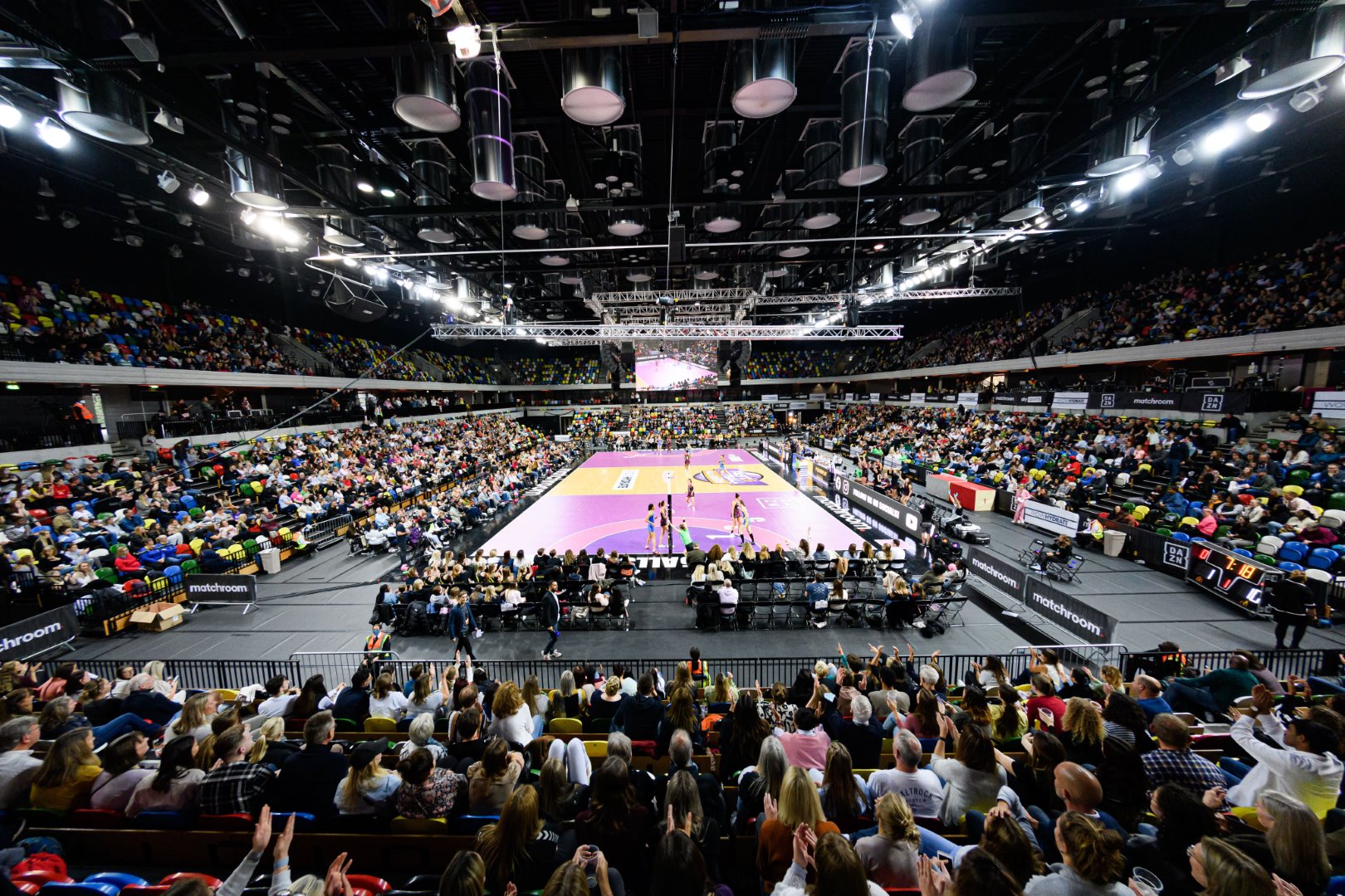 An event photo inside the Copperbox Arena with a packed audience.