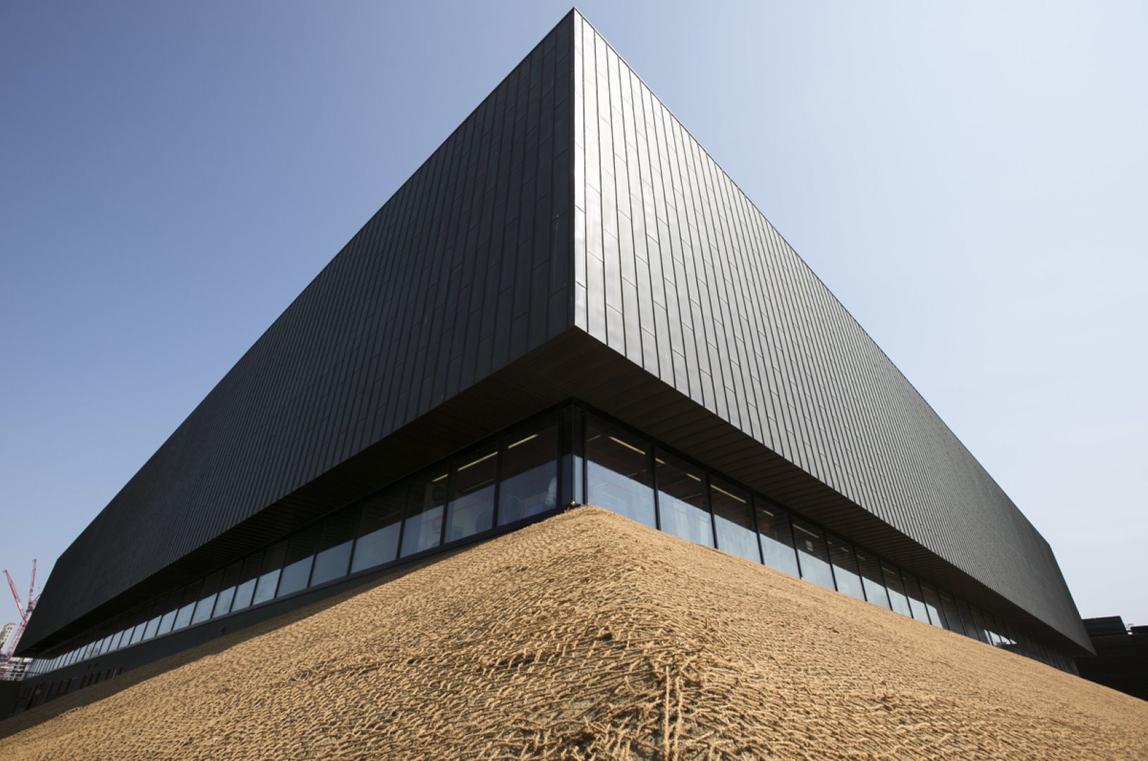 The Copperbox Arena from the outside: a modern, large, dark grey building with glass fronts on the ground floor.